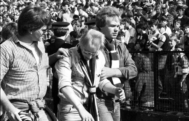 Friends help an injured fan after crowd trouble during the Hibs v Hearts Edinburgh derby football match at Easter Road in August 1984. Final score 1-2 to Hearts.jpg