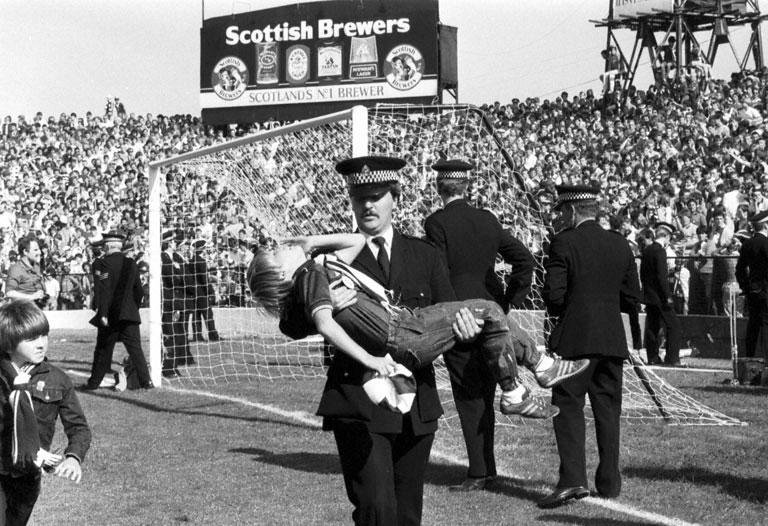 A policeman carries LIttle boy injured after crowd trouble during the Hibs v Hearts Edinburgh derby football match at Easter Road in August 1984. Final score 1-2 to Hearts..jpg