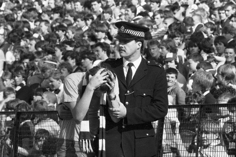 A policeman helps an injured fan after crowd trouble during the Hibs v Hearts Edinburgh derby football match at Easter Road in August 1984. Final score 1-2 to Hearts.jpg